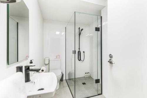 y baño con ducha acristalada y lavamanos. en Modern Studio + Prime Location en Auckland