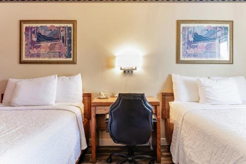 a hotel room with two beds and a desk with a chair at Knights Inn Madera in Madera