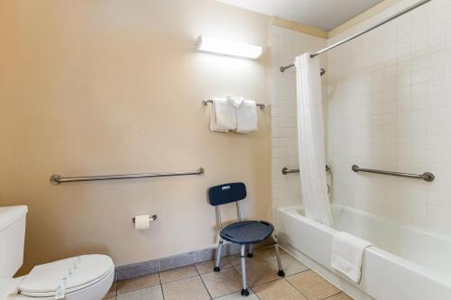 a bathroom with a toilet and a tub and a stool at Knights Inn Madera in Madera