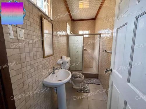 a bathroom with a toilet and a sink at S&S Guyana Real Estate Apartment in Georgetown