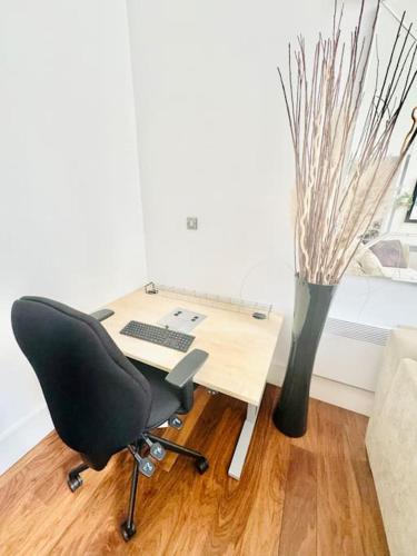 a desk with a computer and a chair and a vase at Exclusive City Apartment - Very Spacious in Sheffield