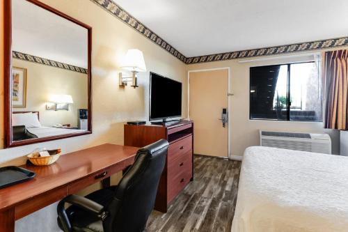 a hotel room with a desk and a bed and a television at Knights Inn Madera in Madera