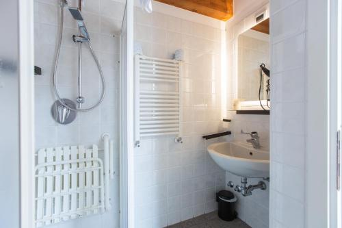 a white bathroom with a sink and a shower at Albergo Del Sole in Varenna