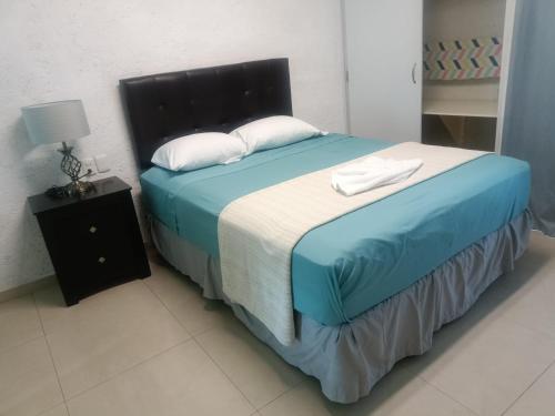 1 dormitorio con 1 cama con sábanas azules y almohadas blancas en Hotel Dos Mundos, Isla Cozumel en Cozumel