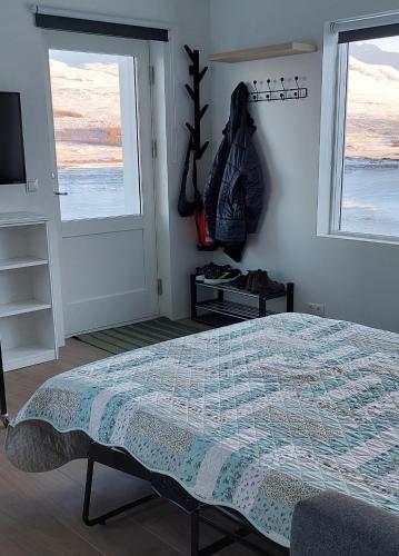 1 dormitorio con 1 cama, TV y ventanas en Tungukot sumarhús, en Akureyri