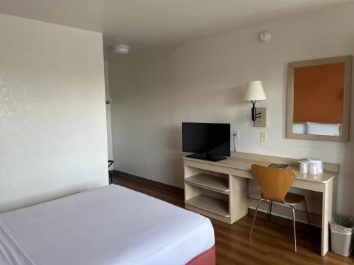 a hotel room with a bed and a desk with a television at Motel 6-Stanton, CA- Anaheim West in Stanton