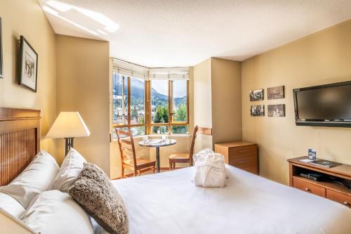 a bedroom with a large bed and a television at Cascade by Elevate Vacations in Whistler
