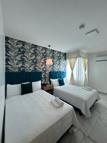a bedroom with two beds and a wall with plants at Hotel Presidente Beach Playas in Playas