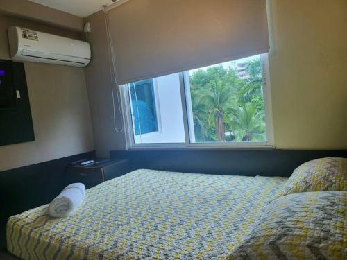 a bedroom with a bed and a window with a palm tree at R.7-7 Lindo estudio de 2 recámaras, zona turística in Panama City