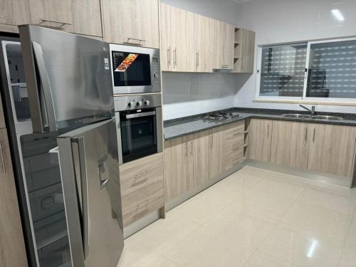 una cocina con electrodomésticos de acero inoxidable y armarios de madera en BemVinda Sweet Home - Cama Mesa e Fogão en Praia