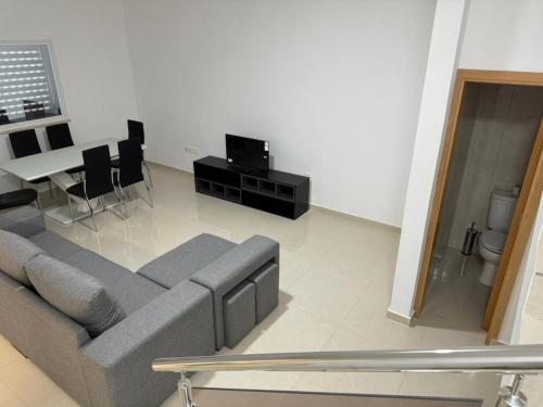 a living room with a gray couch and a table at BemVinda Sweet Home - Cama Mesa e Fogão in Praia