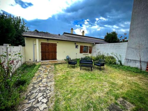 a yard with chairs and a house with a fence at Little house (near Paris & Airport) in Drancy
