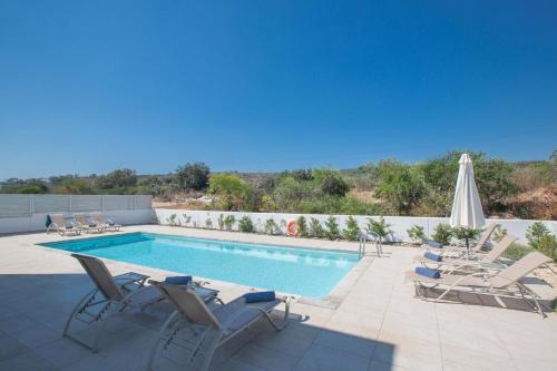 einen Pool mit Liegestühlen und einem Sonnenschirm in der Unterkunft Ferienhaus für 10 Personen in Protaras, Südküste von Zypern - b59033 in Protaras