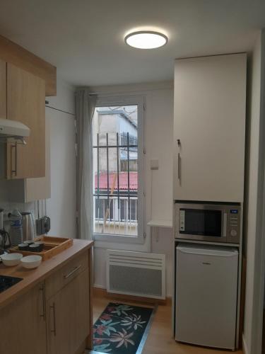 d'une cuisine équipée d'un four micro-ondes et d'une fenêtre. dans l'établissement Bel appartement à deux pas de paris, à Saint-Ouen