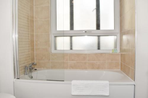bagno con vasca e finestra di Vibrant Serviced Apartment In Central Birmingham a Birmingham