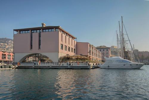 una barca è ormeggiata accanto a un edificio in acqua di NH Collection Genova Marina a Genova