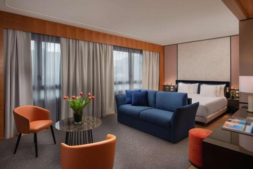 una camera d'albergo con un letto e un divano blu di NH Collection Genova Marina a Genova