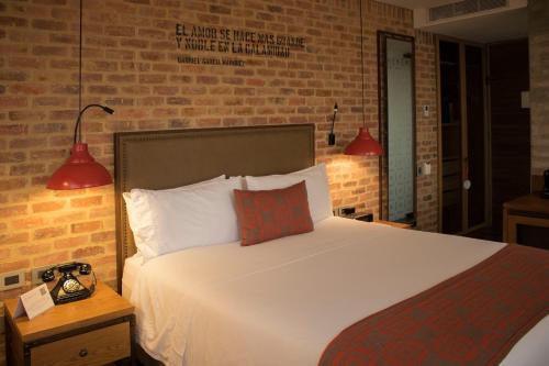 a bedroom with a bed and a brick wall at The Artisan D.C. Hotel, Autograph Collection in Bogotá
