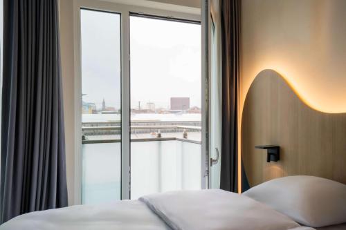 um quarto de hotel com uma cama e uma grande janela em prizeotel Dresden-Mitte em Dresden