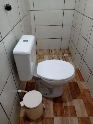 a bathroom with a white toilet and a trash can at Kitnet aconchegante in Olinda