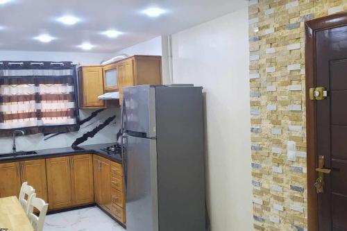 La cuisine est équipée d'un réfrigérateur en acier inoxydable et de placards en bois. dans l'établissement Un appart moderne et neuf, à Tlemcen