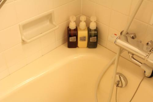 a bathroom with a bath tub with three bottles on it at Hotel Saika in Fujisawa