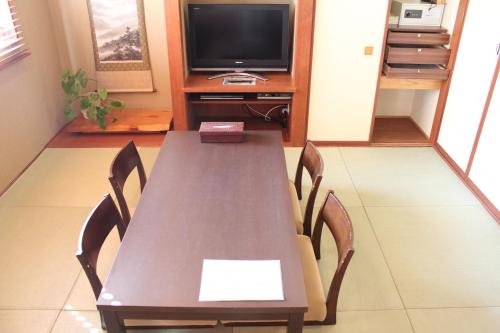 a dining room table with chairs and a television at Hotel Saika in Fujisawa
