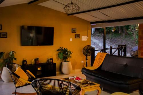 ein Wohnzimmer mit einem Sofa, Stühlen und einem TV in der Unterkunft Extraordinario chalet a 1h de Bta in San Antonio del Tequendama