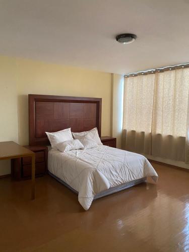 Schlafzimmer mit einem Bett mit einem Kopfteil aus Holz und einem Fenster in der Unterkunft Departamento Zocalo ,ADE in Mexiko-Stadt