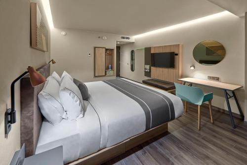 a hotel room with a large bed and a desk at City Express Plus by Marriott Cancun Aeropuerto Riviera in Cancún