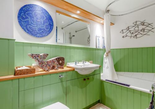 een groene badkamer met een wastafel en een spiegel bij Olive Tree Cottage in Portesham