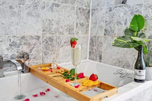 eine Badewanne mit einem Holztablett mit einem Champagnerglas und Obst in der Unterkunft Spacious 2 Bed Ensuite - Workspace, high-speed Wi-Fi in London