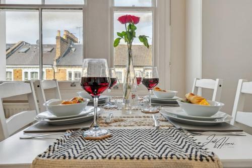 einen Tisch mit Gläsern Wein und Essen drauf in der Unterkunft Spacious 2 Bed Ensuite - Workspace, high-speed Wi-Fi in London
