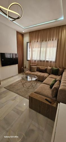 a living room with a large couch and a table at Cosy & Confort Studio près de l'aéroport in Nouaceur
