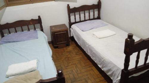 two twin beds in a small room with a table at Apartamentos da Matriz in Piumhi