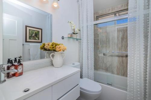 a white bathroom with a toilet and a shower at Oasis with heated pool, mini golf, hot tub & barbq area in Oceanside