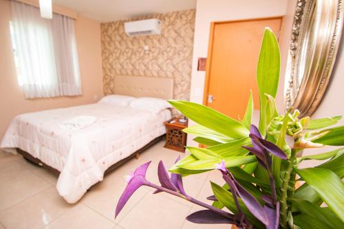 a bedroom with a bed and a potted plant at Flat Tropical Caribessa in João Pessoa