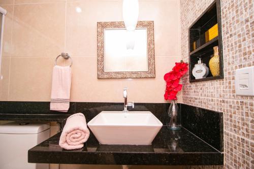 a bathroom with a sink and a mirror at Flat Tropical Caribessa in João Pessoa