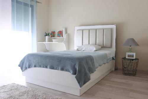 a bedroom with a white bed with a blue blanket at Espaço Jandira in Fajã de Baixo