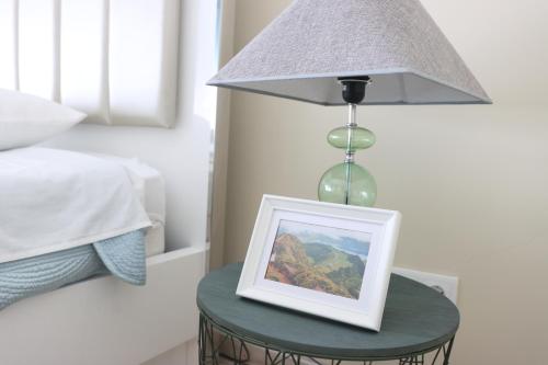 a lamp with a picture on a table next to a bed at Espaço Jandira in Fajã de Baixo