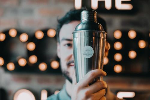 a man is holding up a glass bottle at The Artisan D.C. Hotel, Autograph Collection in Bogotá