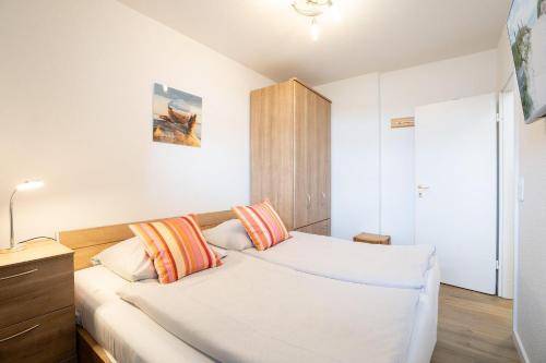 Schlafzimmer mit einem Bett mit orangefarbenen und weißen Kissen in der Unterkunft Berliner Hof - HOF/210 in Scharbeutz