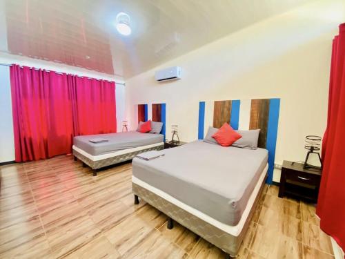 twee bedden in een kamer met rode gordijnen bij Cozy dog-friendly apt w/shared pool - close to Tamarindo in Huacas