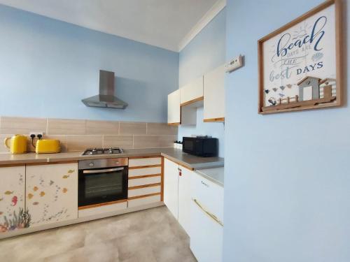 a kitchen with white cabinets and a sign on the wall at The Octopus - at Largs Town Centre with Private Parking in Largs