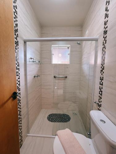 a shower with a glass door in a bathroom at Apart Avenida Monte Verde in Monte Verde