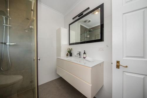 a white bathroom with a sink and a shower at High Vista in Mount Eliza with Pool in Mount Eliza