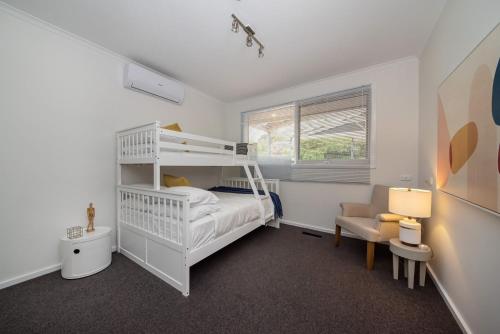 a bedroom with a white bunk bed and a chair at High Vista in Mount Eliza with Pool in Mount Eliza