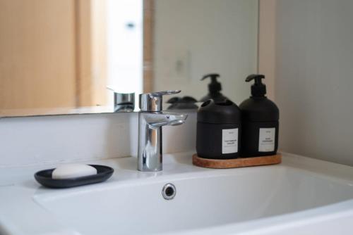 een wastafel in de badkamer met 2 flessen zeep en een spiegel bij studio cosy Maarif stade med V in Casablanca