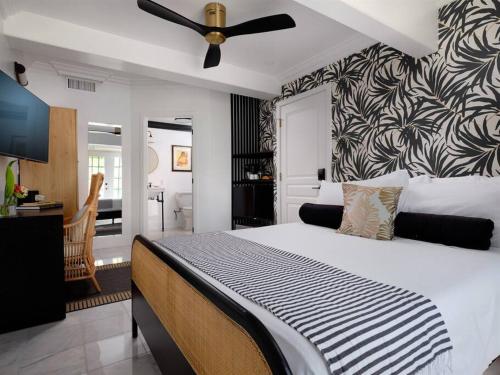 a bedroom with a large bed with a ceiling fan at The Lehua Suite at the Historic Wailuku Inn Maui in Wailuku