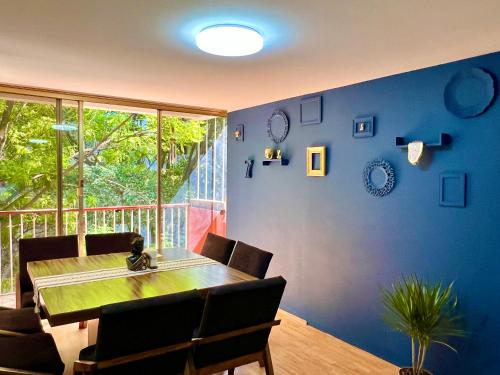 a dining room with a table and a blue wall at Casa Camara in Mexico City